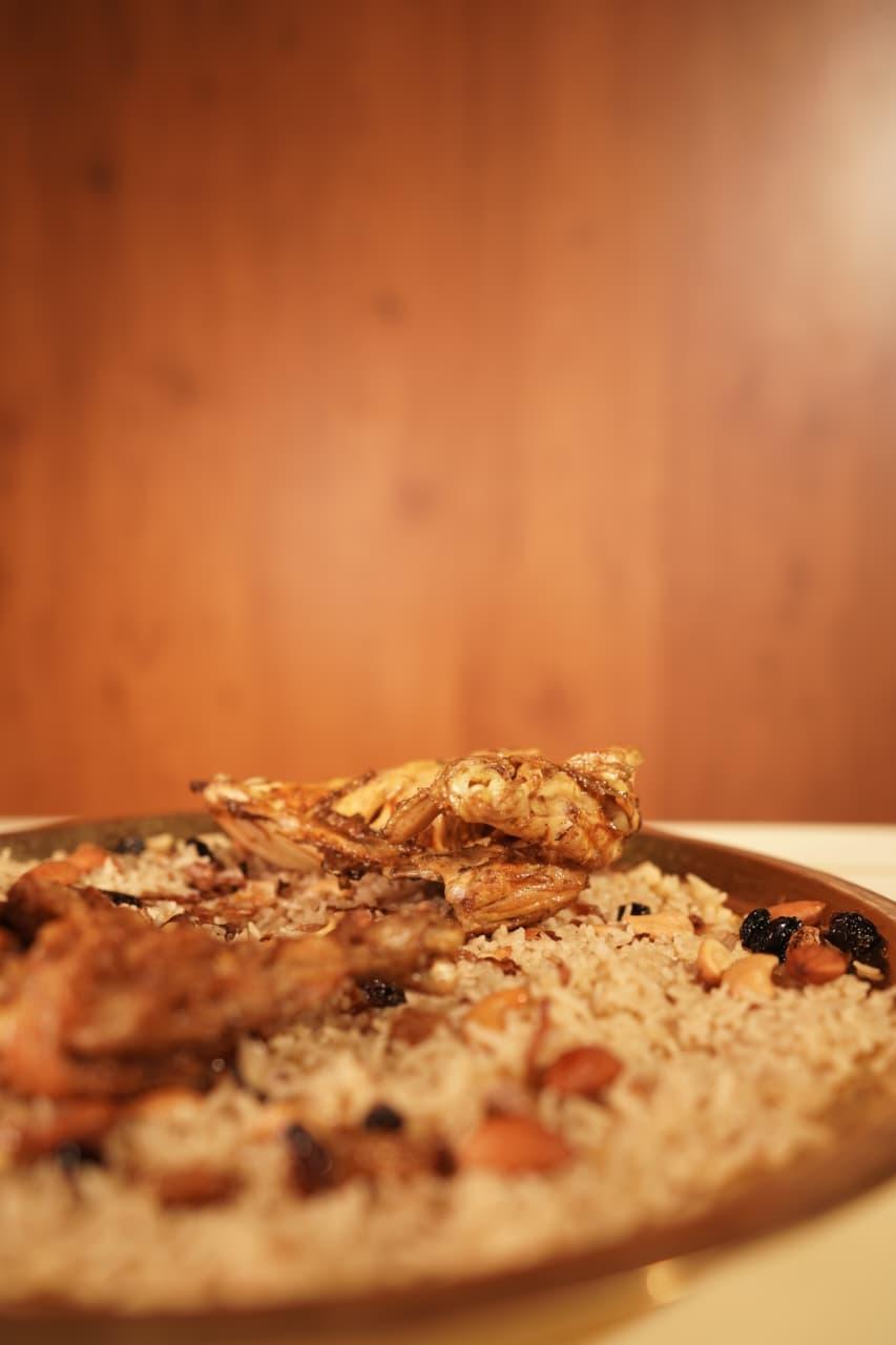 Chicken mandi on a brass platter of rice with almonds and raisins