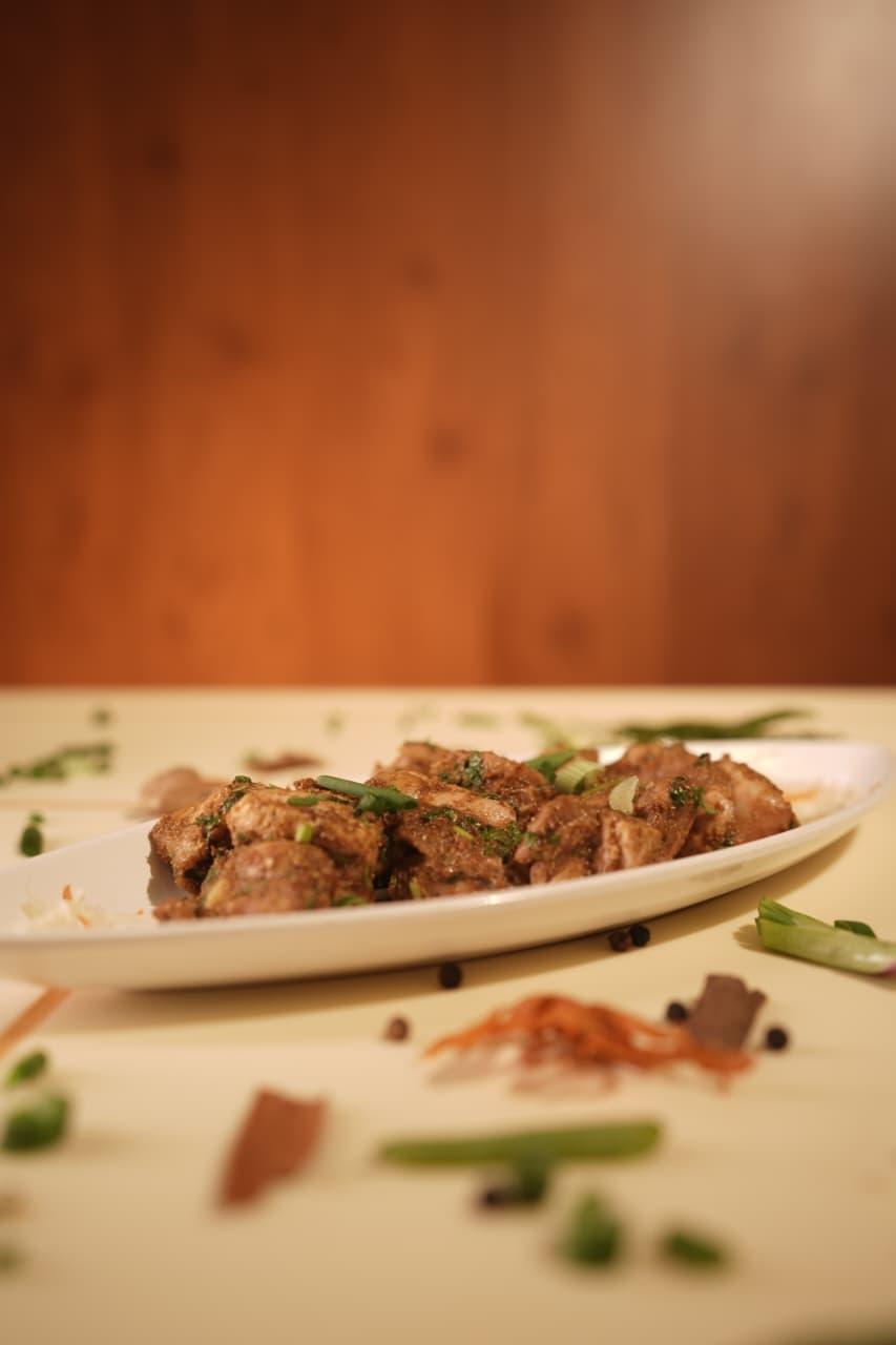 Pepper chicken dry on an oval plate garnished with spring onion