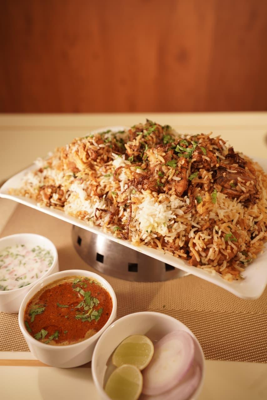 Chicken biryani platter with raita, salan, lemon and onion