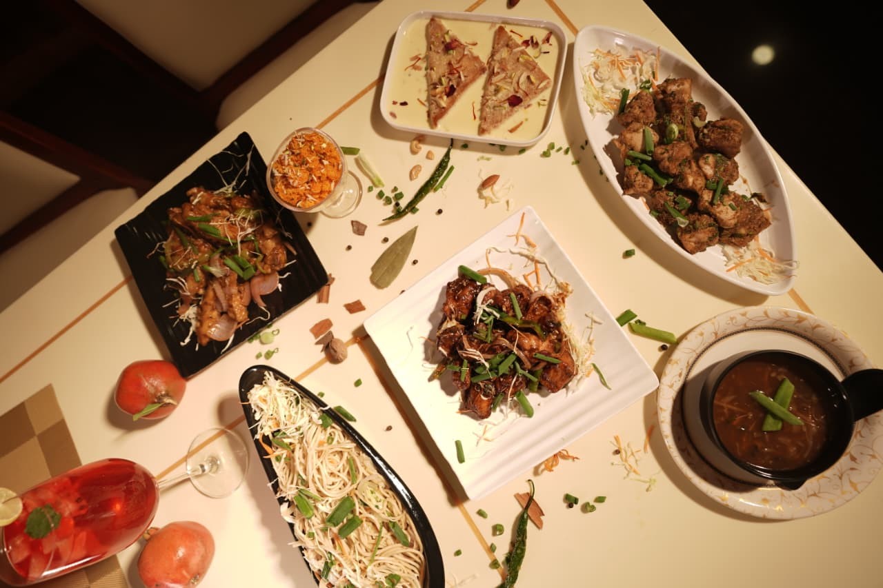 Overhead view of a table spread with starters, noodles, soup and dessert