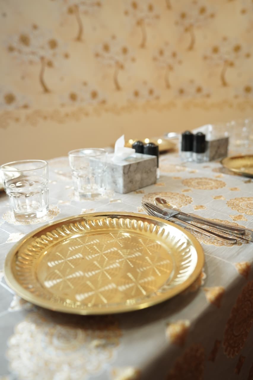 Brass plate and cutlery on a gold-patterned tablecloth