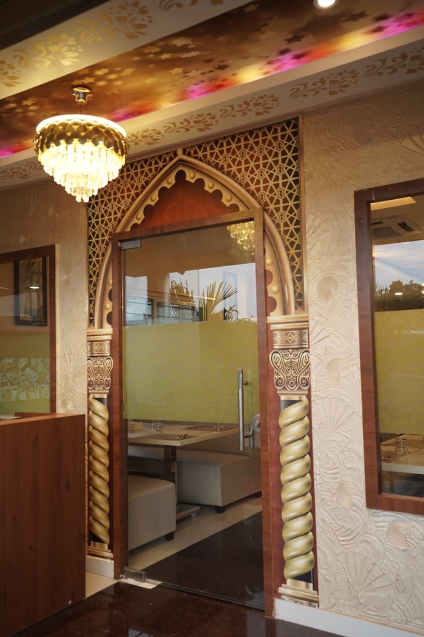 Carved Arabic arch doorway with twisted gold columns beneath a crystal chandelier at Al-Quds