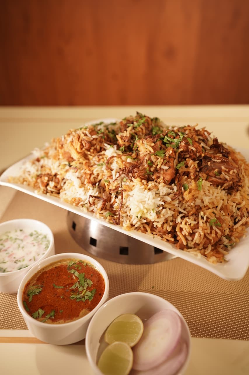 Chicken biryani platter with raita and salan
