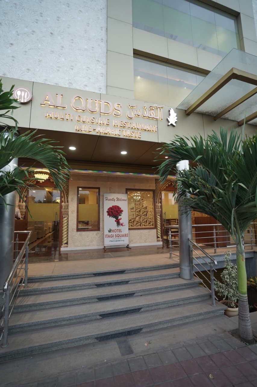 The Al-Quds entrance at Hotel Itagi Square, with its lit sign above the steps